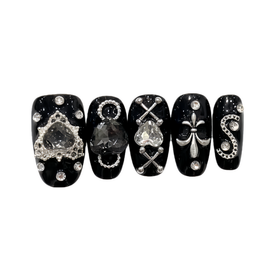 Black nail art designs with various symbols and rhinestones on a white background