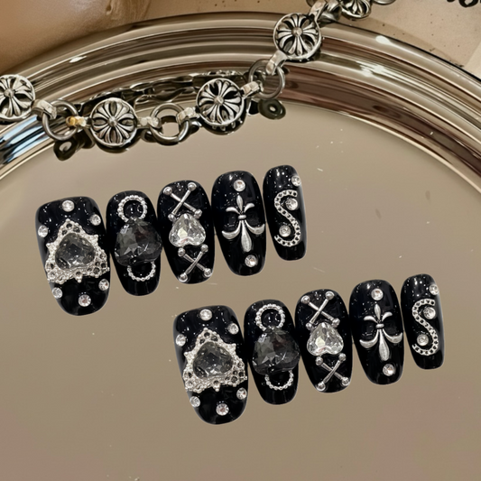 Black nail art with decorative designs on a mirror surface