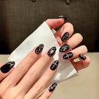 Hand with black nail art holding a white napkin against a dark background