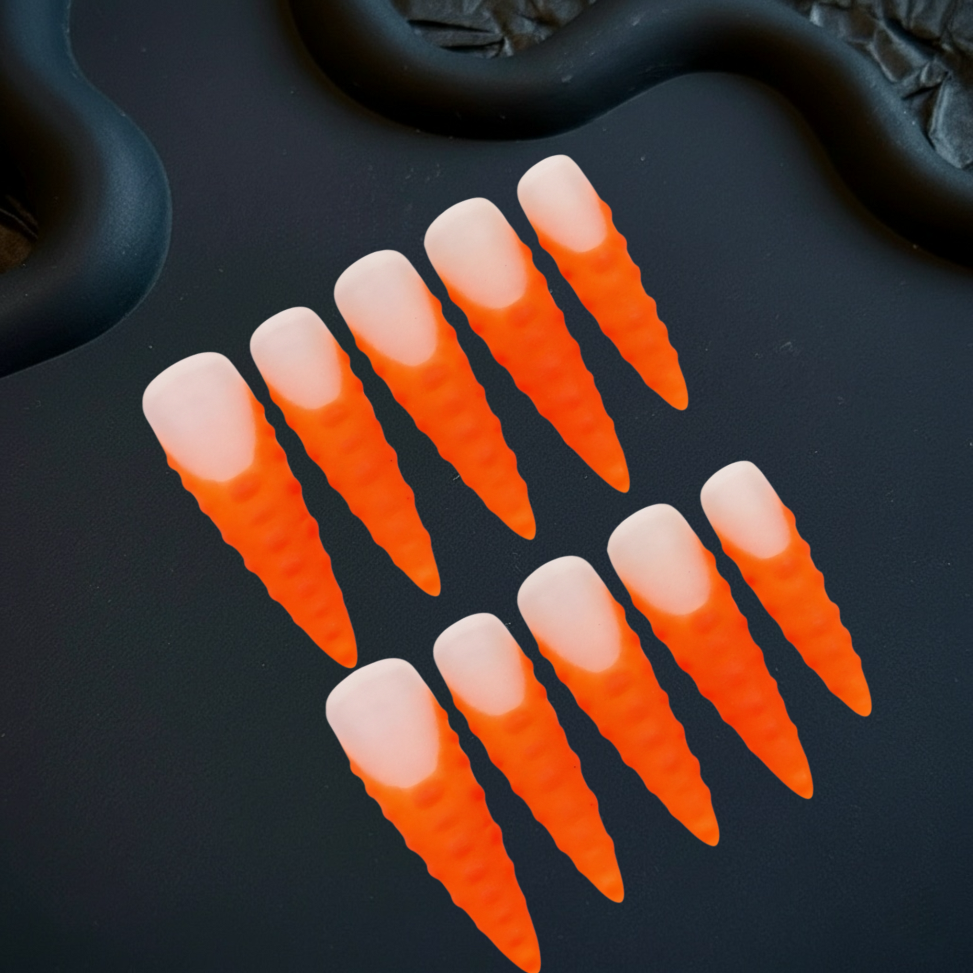 Set of orange and white gradient nail tips on a black background