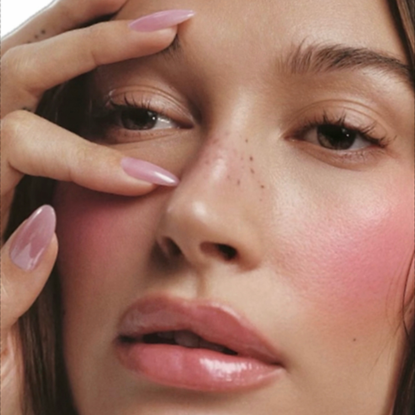 Close-up of a person's face with a hand touching their cheek, highlighting skin texture.