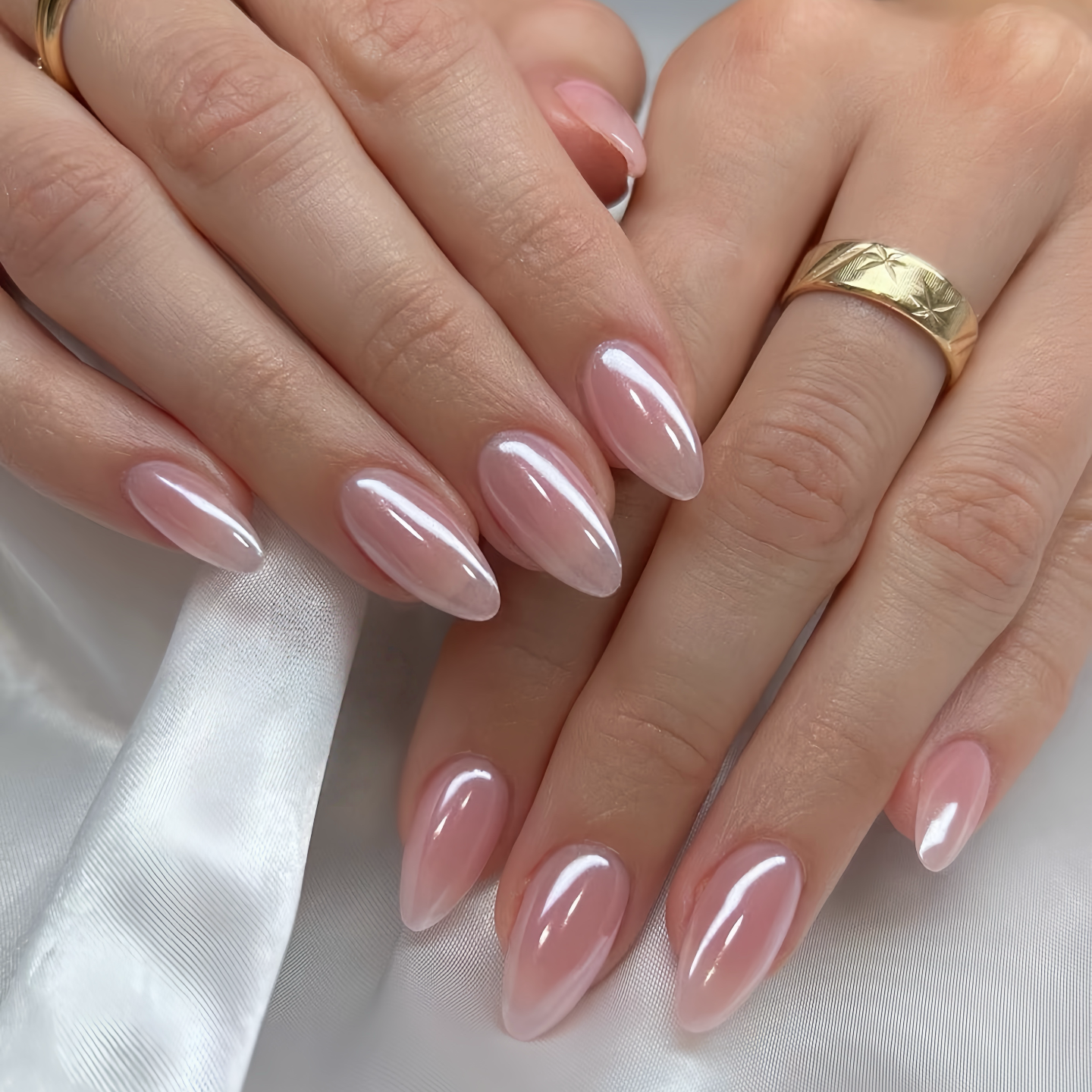 Close-up of hands with pink nail polish on a white fabric background