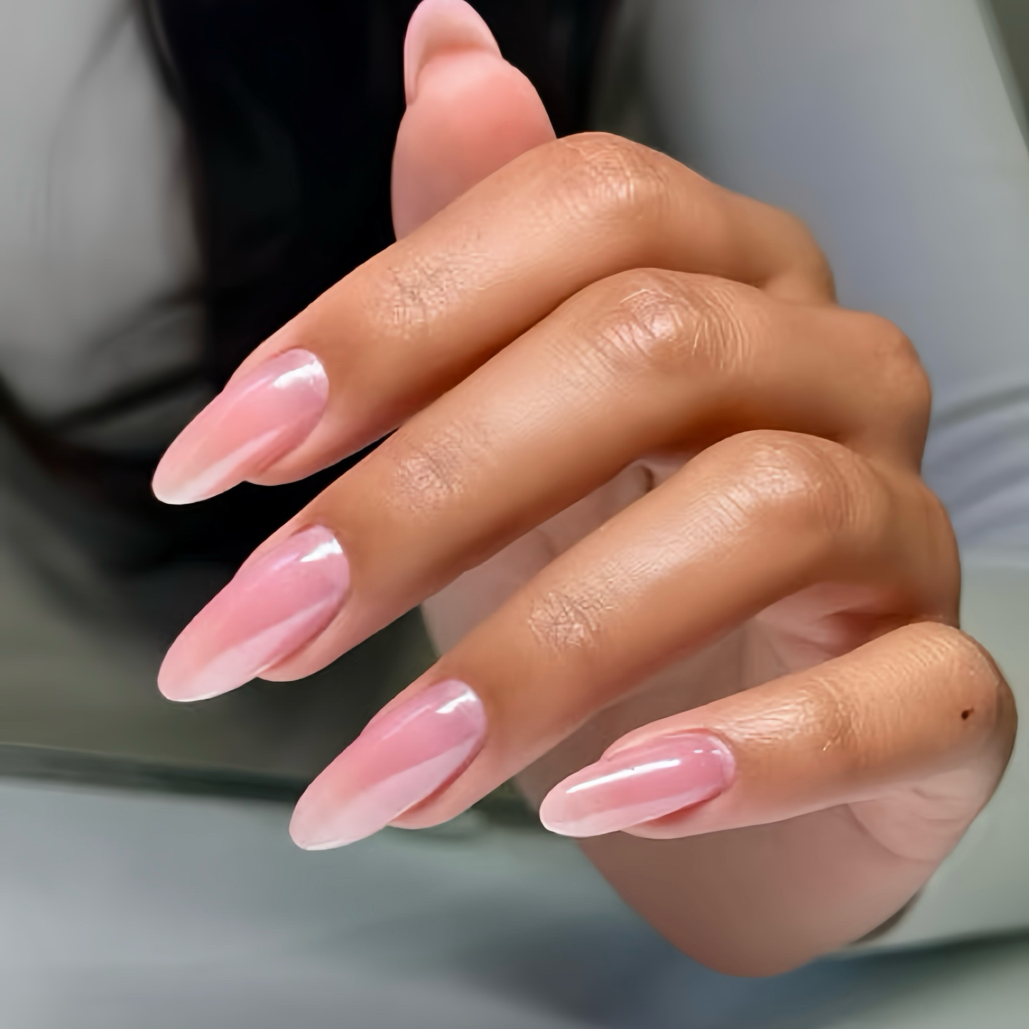 Close-up of a hand with pink nail polish on a blurred background