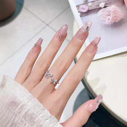 Hand with pink nail polish and butterfly rings on a light background