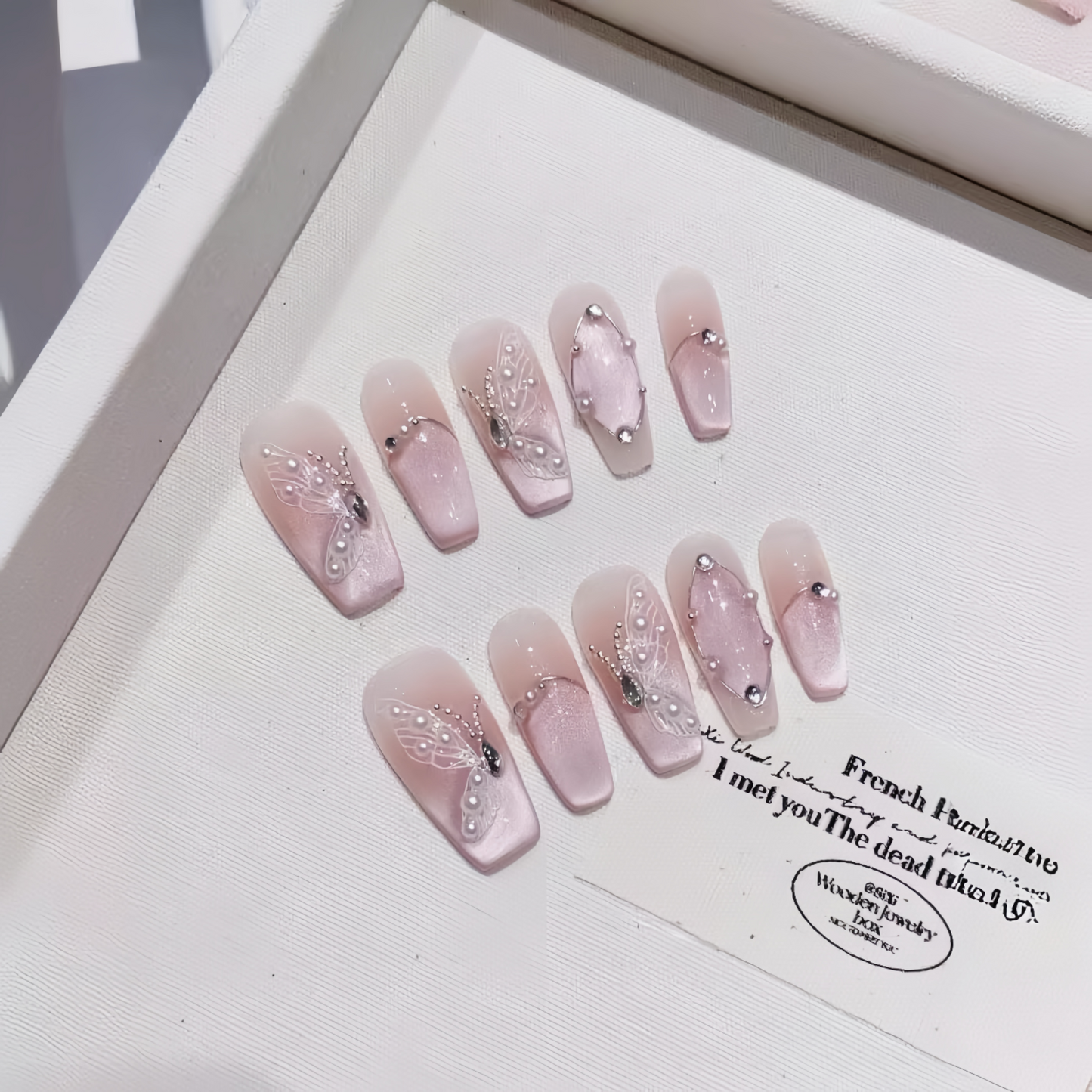 Set of pink nail art designs with rhinestones on a white background