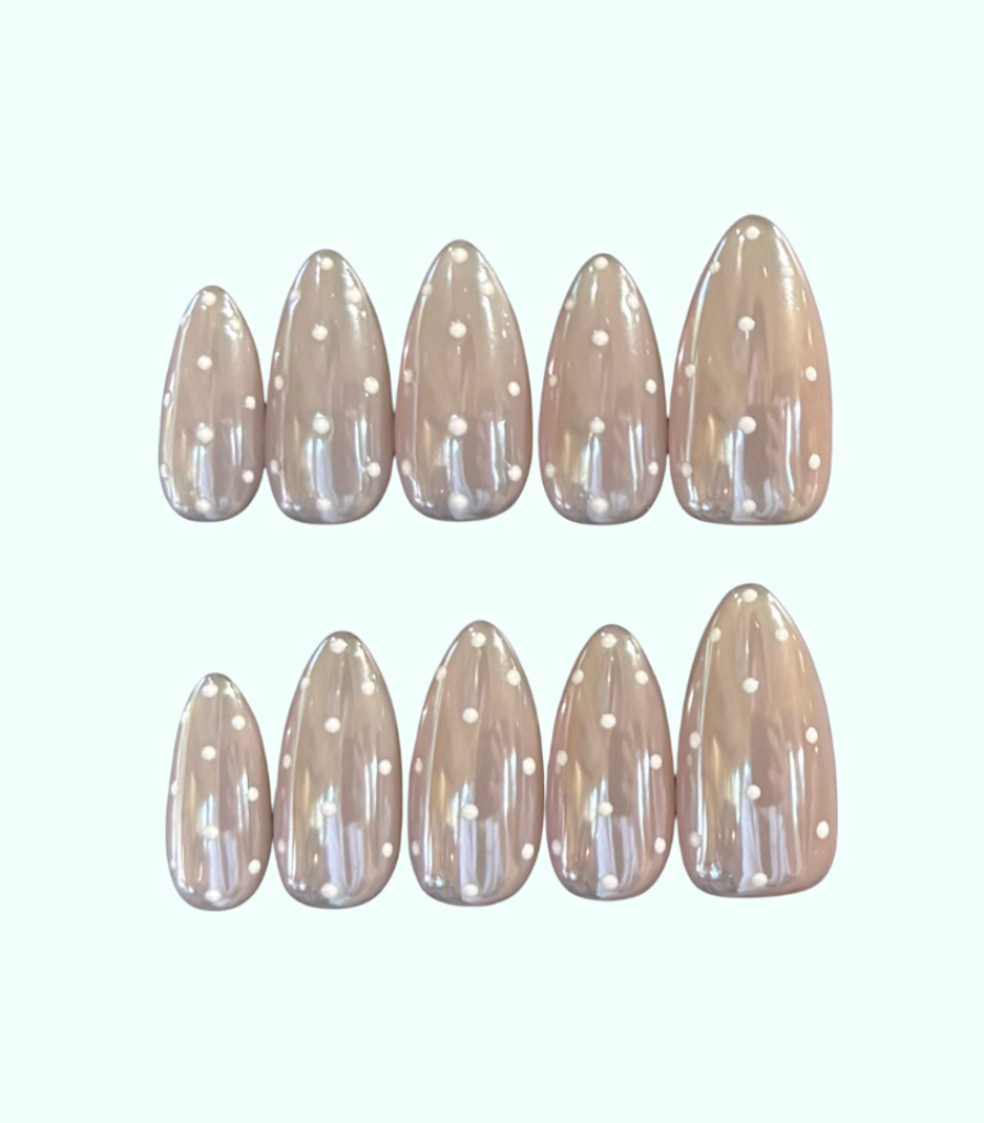 Set of beige nail extensions with white polka dots on a white background