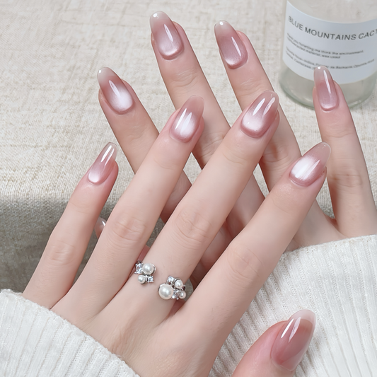 Close-up of hands with pink nail polish and pearl ring on a neutral background