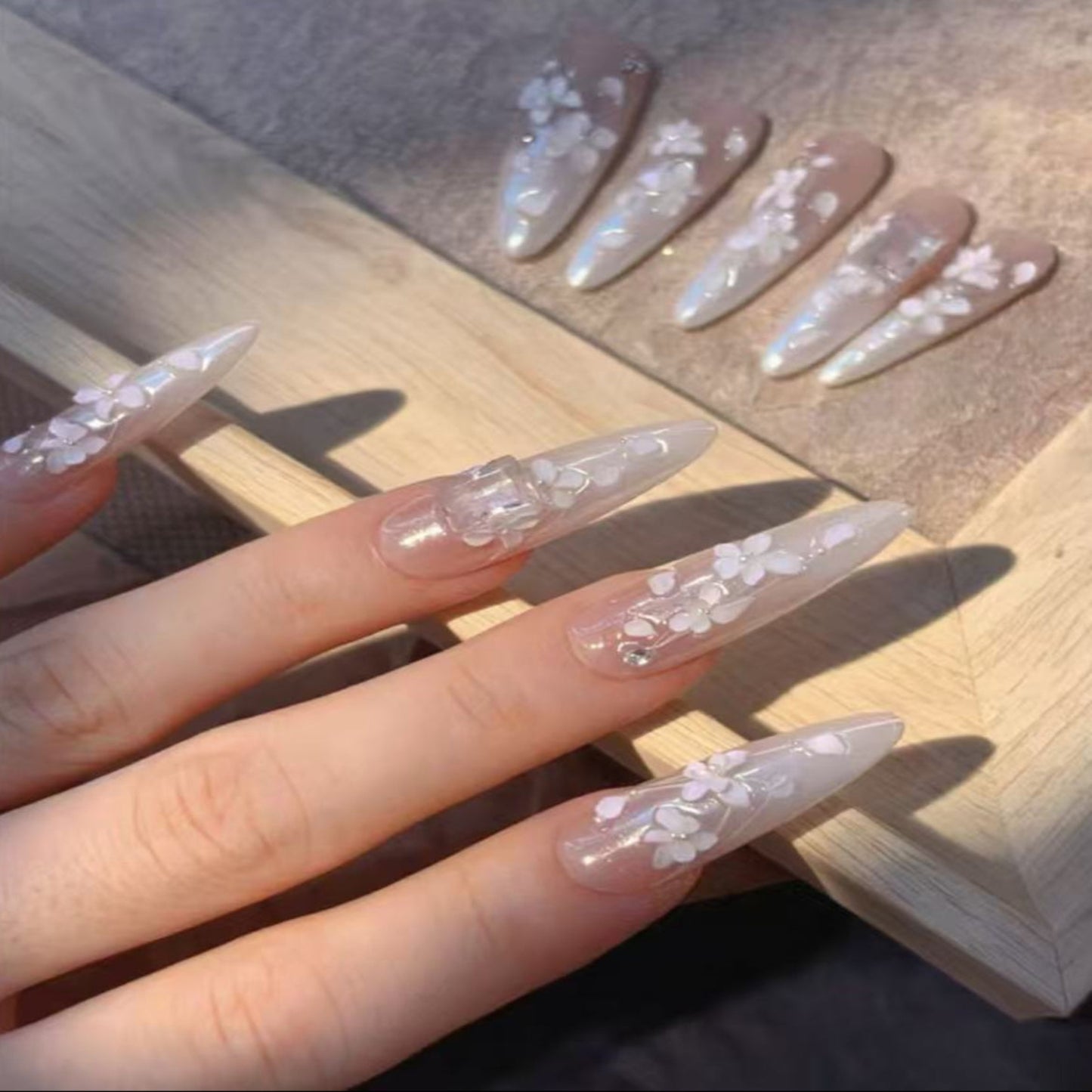 Almond-shaped nails with floral designs on a wooden surface