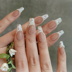 Close-up of a hand with decorative nail art holding a small plant.