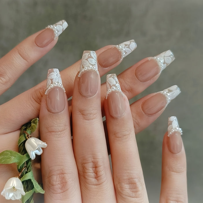 Close-up of a hand with decorative nail art holding a small plant.