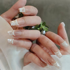 Close-up of hands with decorative nail art holding a small green plant.