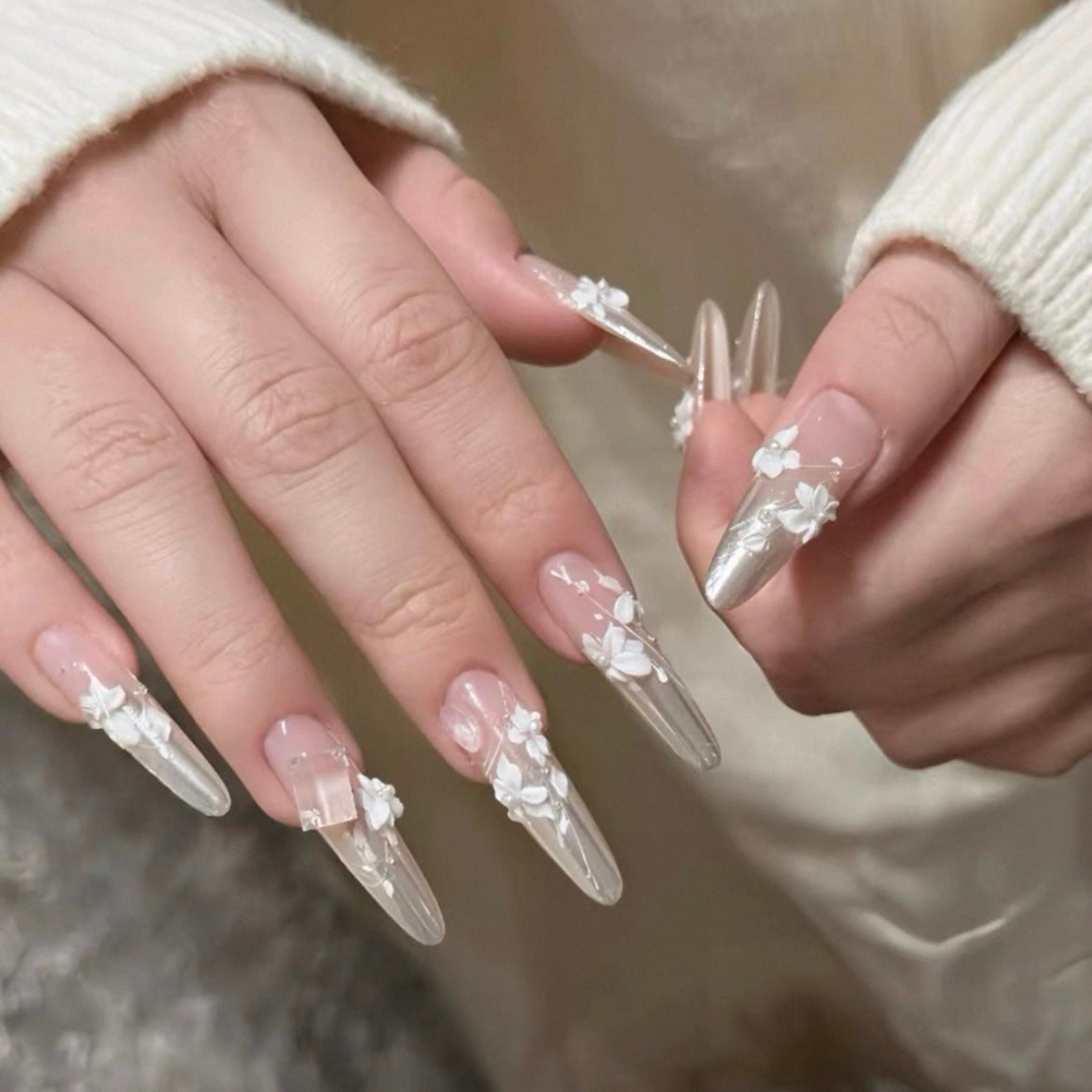 Close-up of hands with decorative nail art on a neutral background