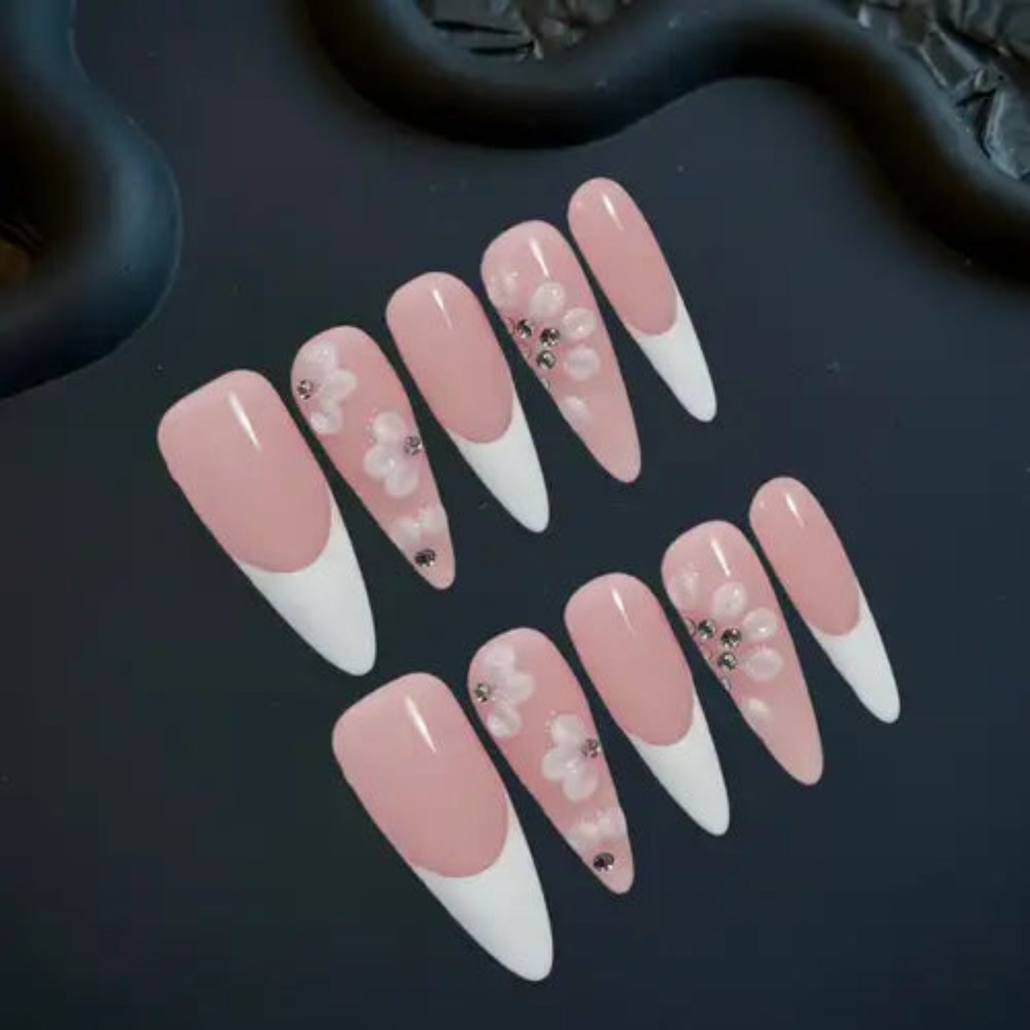 Set of pink and white nail designs with decorative elements on a dark surface
