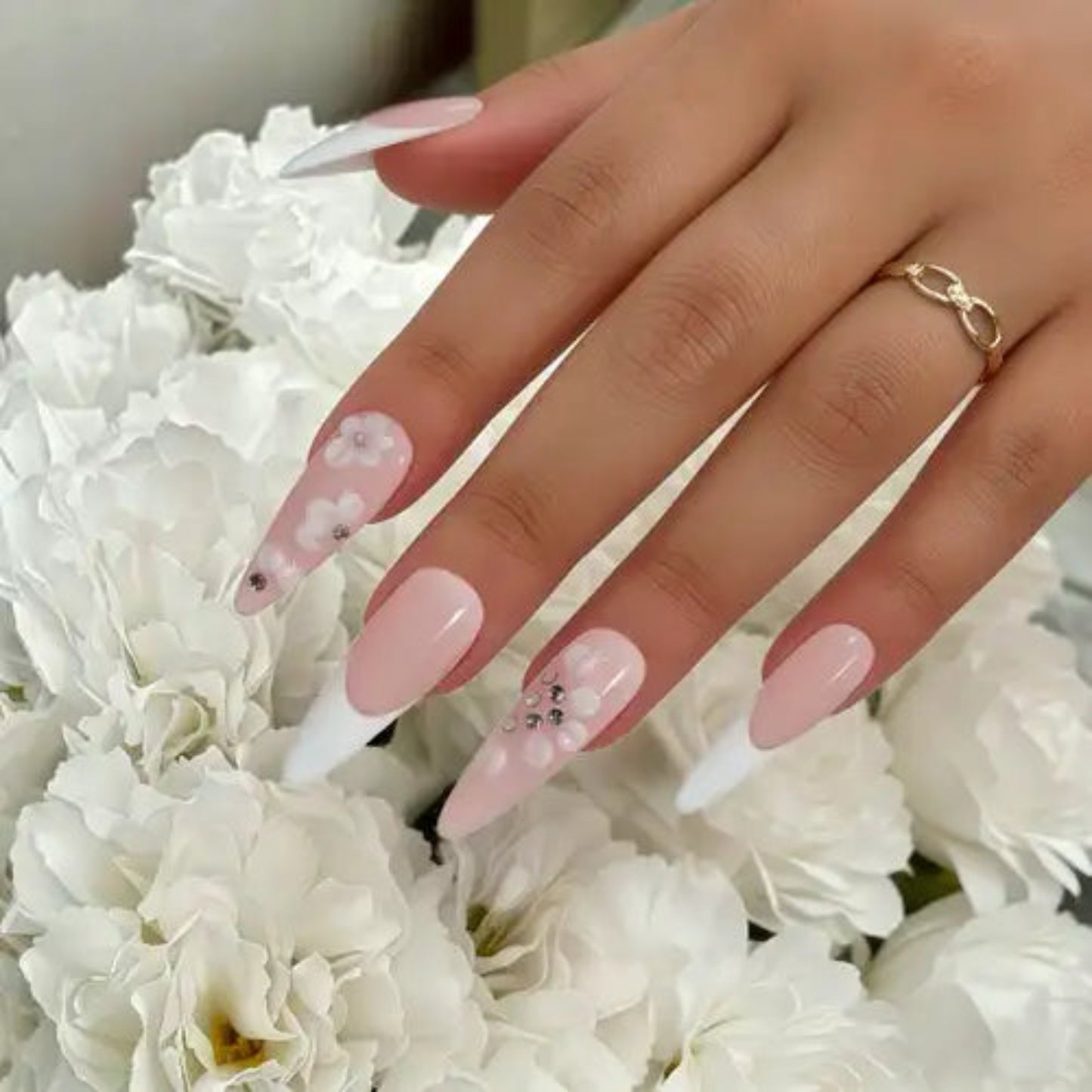 Hand with pink nail polish and white flowers in the background