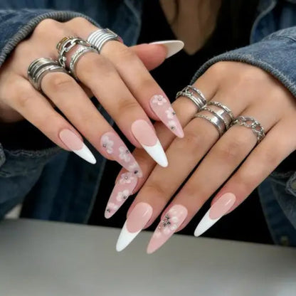 Close-up of hands with pink and white nail polish and multiple silver rings.