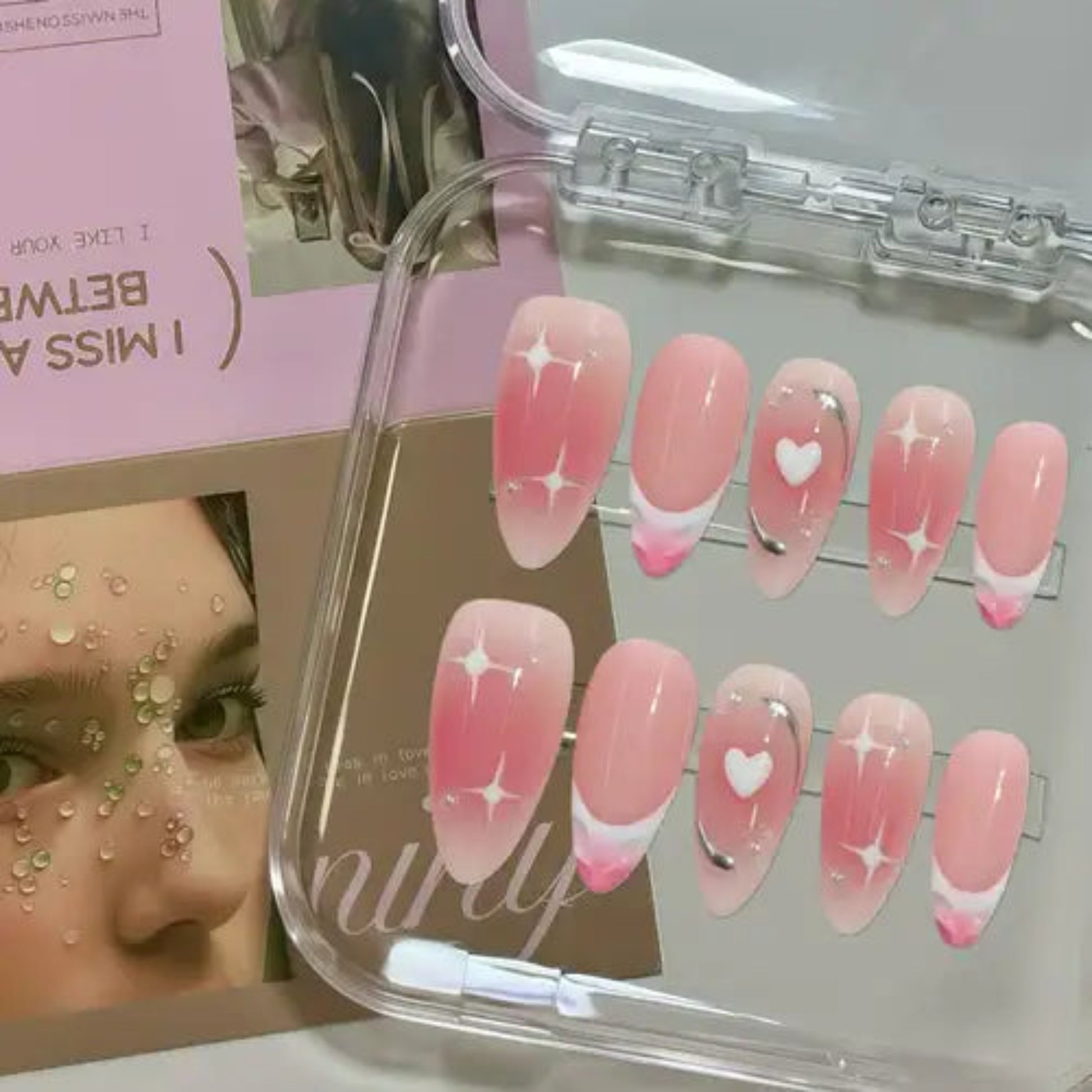 Set of pink nail art designs in a clear case with a blurred background