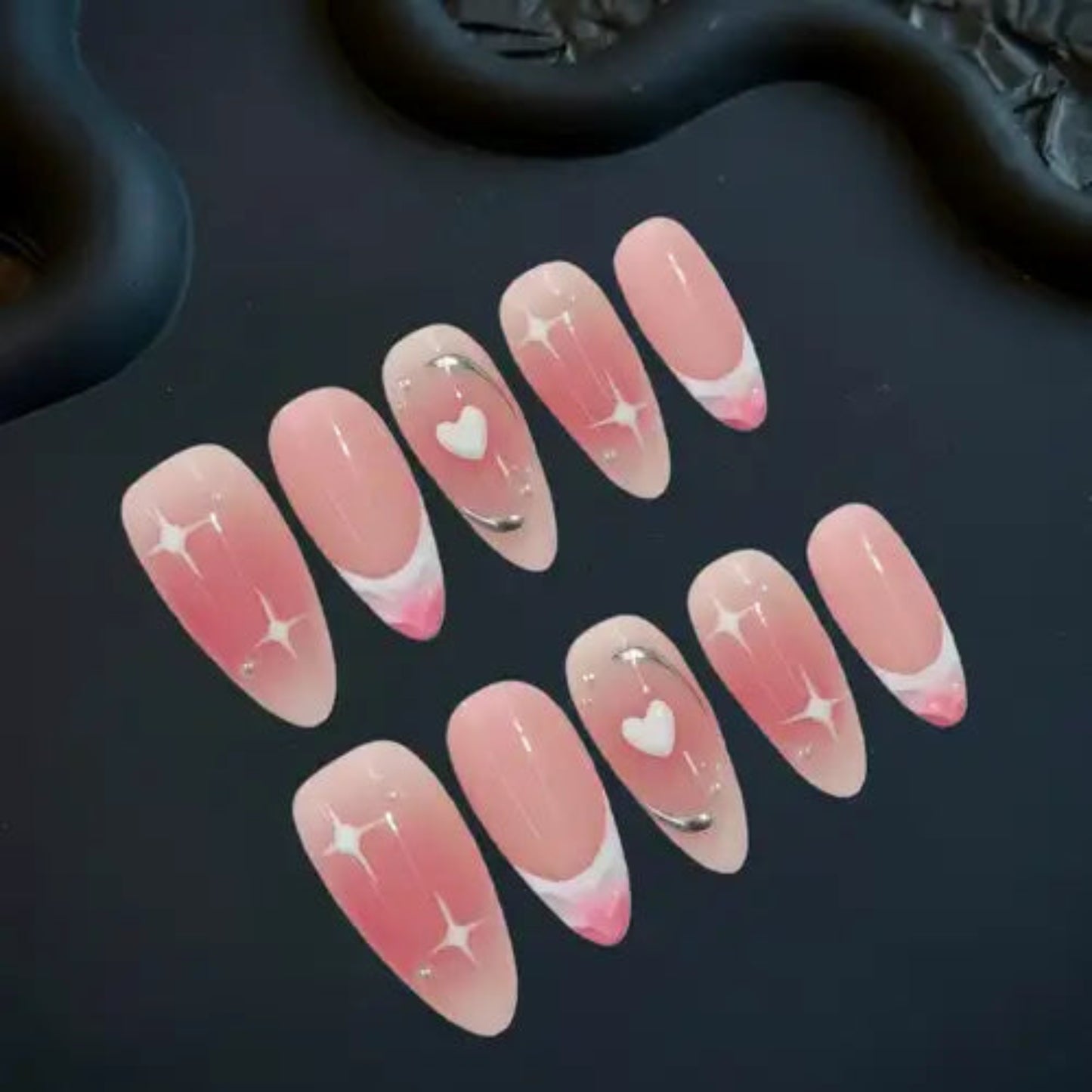 Set of pink and white nail designs with heart and star patterns on a dark background