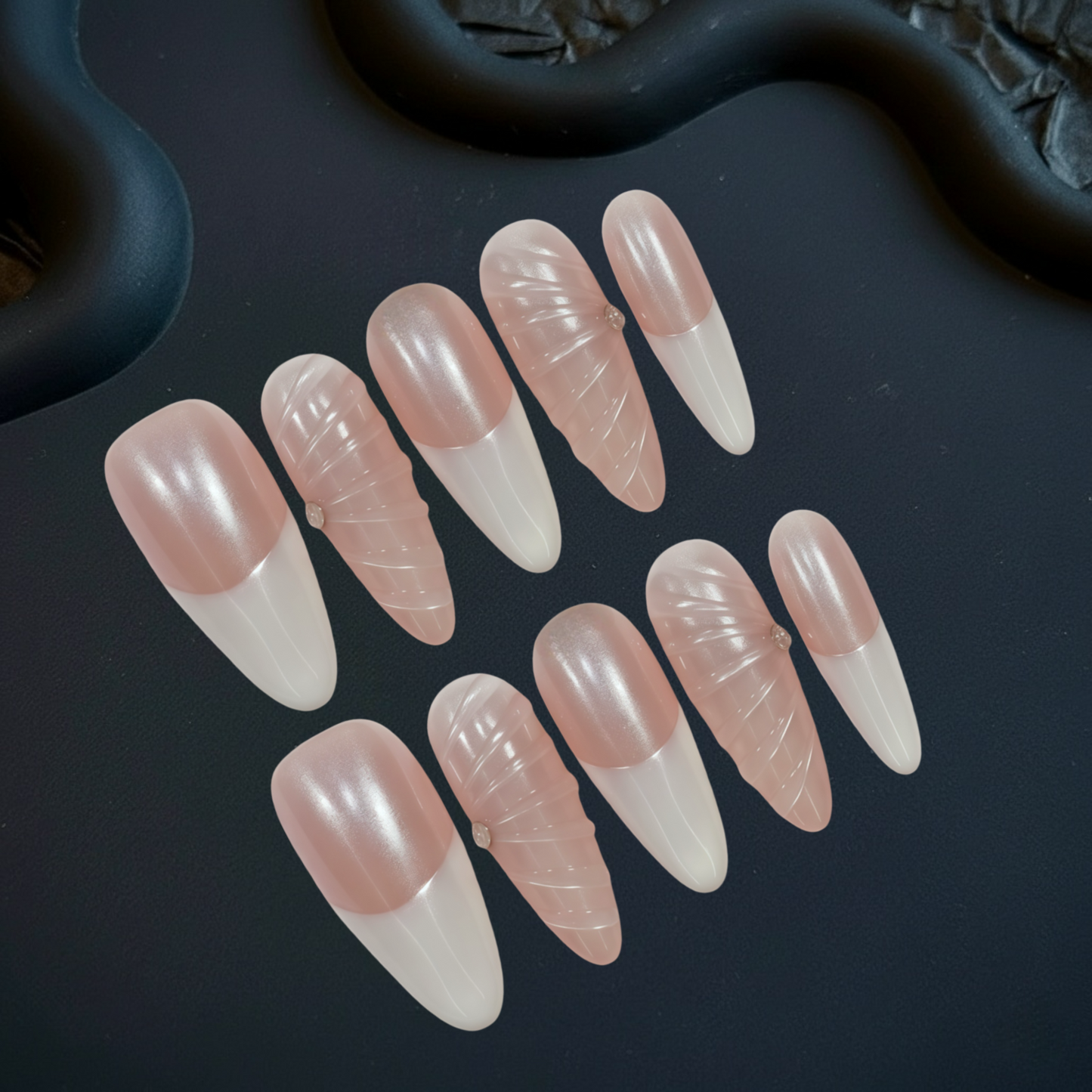 Set of pink and white nail tips on a dark surface