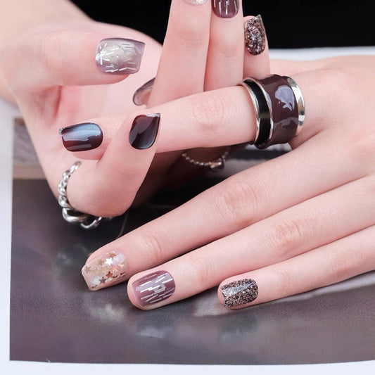 Close-up of hands with decorative nail art and rings on a reflective surface