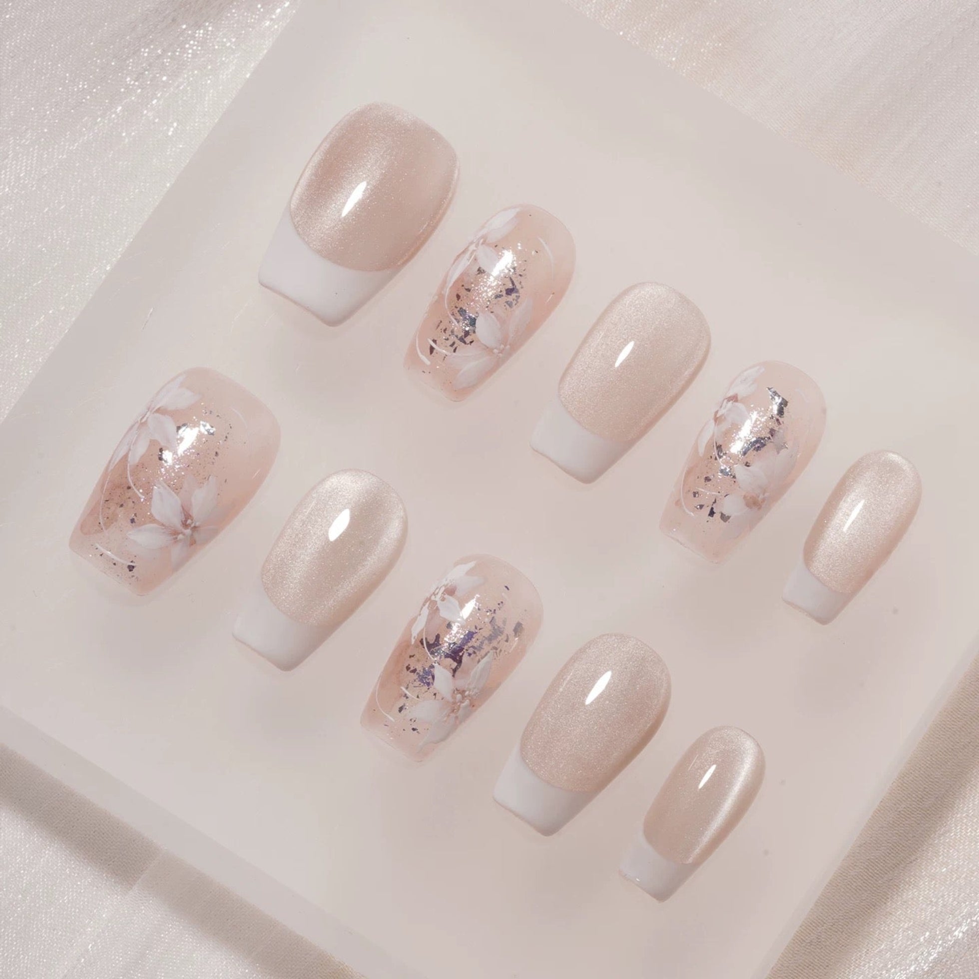 Set of decorative false nails with marble and glitter design on a white tray.