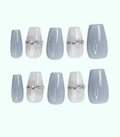 Set of light blue press-on nails with silver decorative bands on a white background