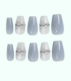 Set of light blue press-on nails with silver decorative bands on a white background