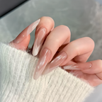 Close-up of a hand with long, clear nail polish on a blurred background