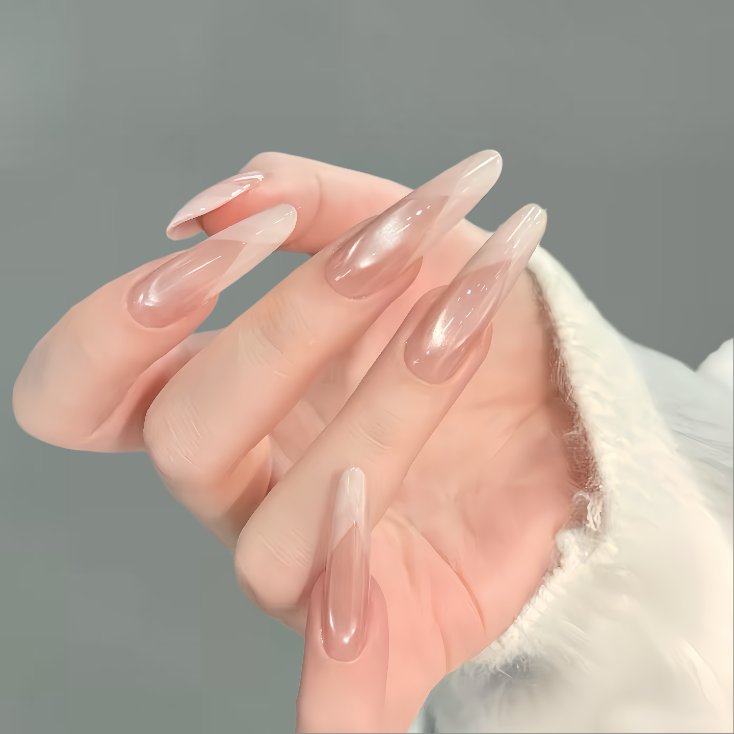 Hand with long, clear acrylic nails on a gray background