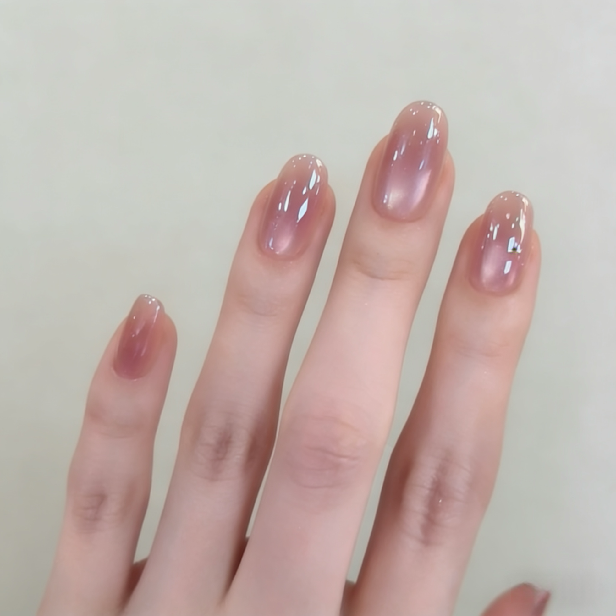 Hand with pink nail polish on a plain background