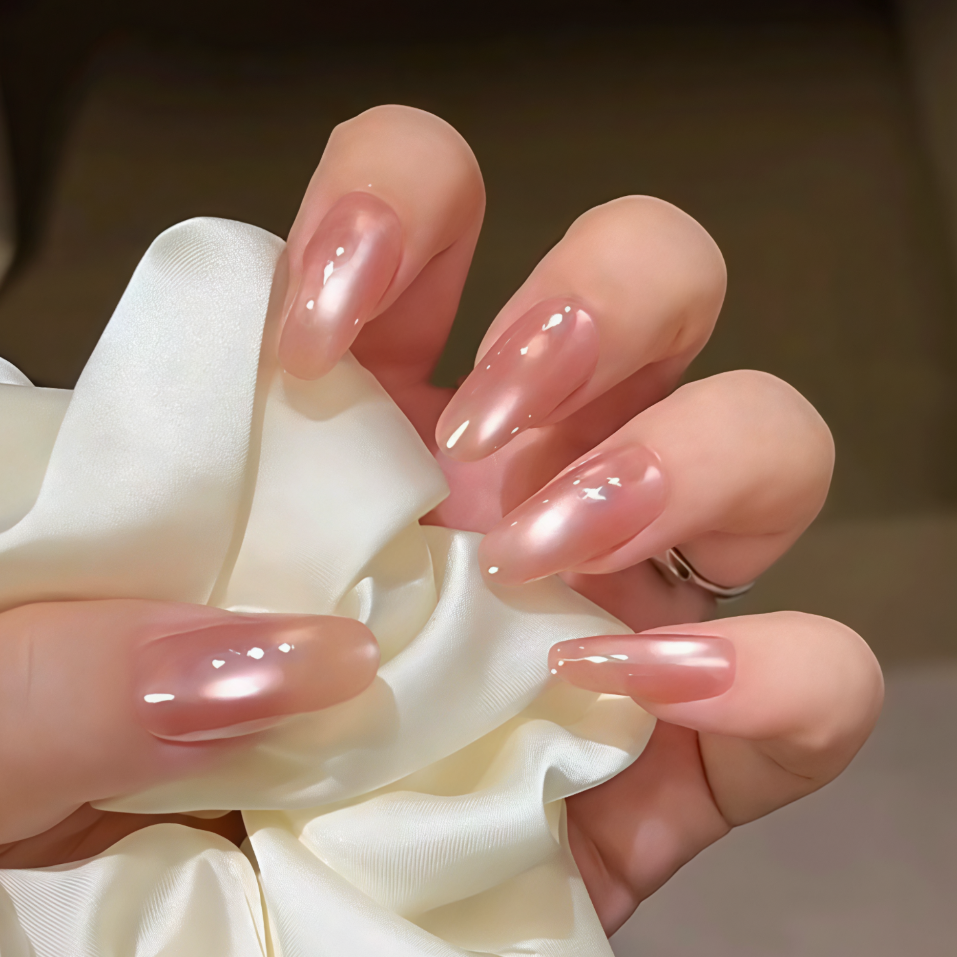 Hand with pink nail polish holding a white flower against a blurred background
