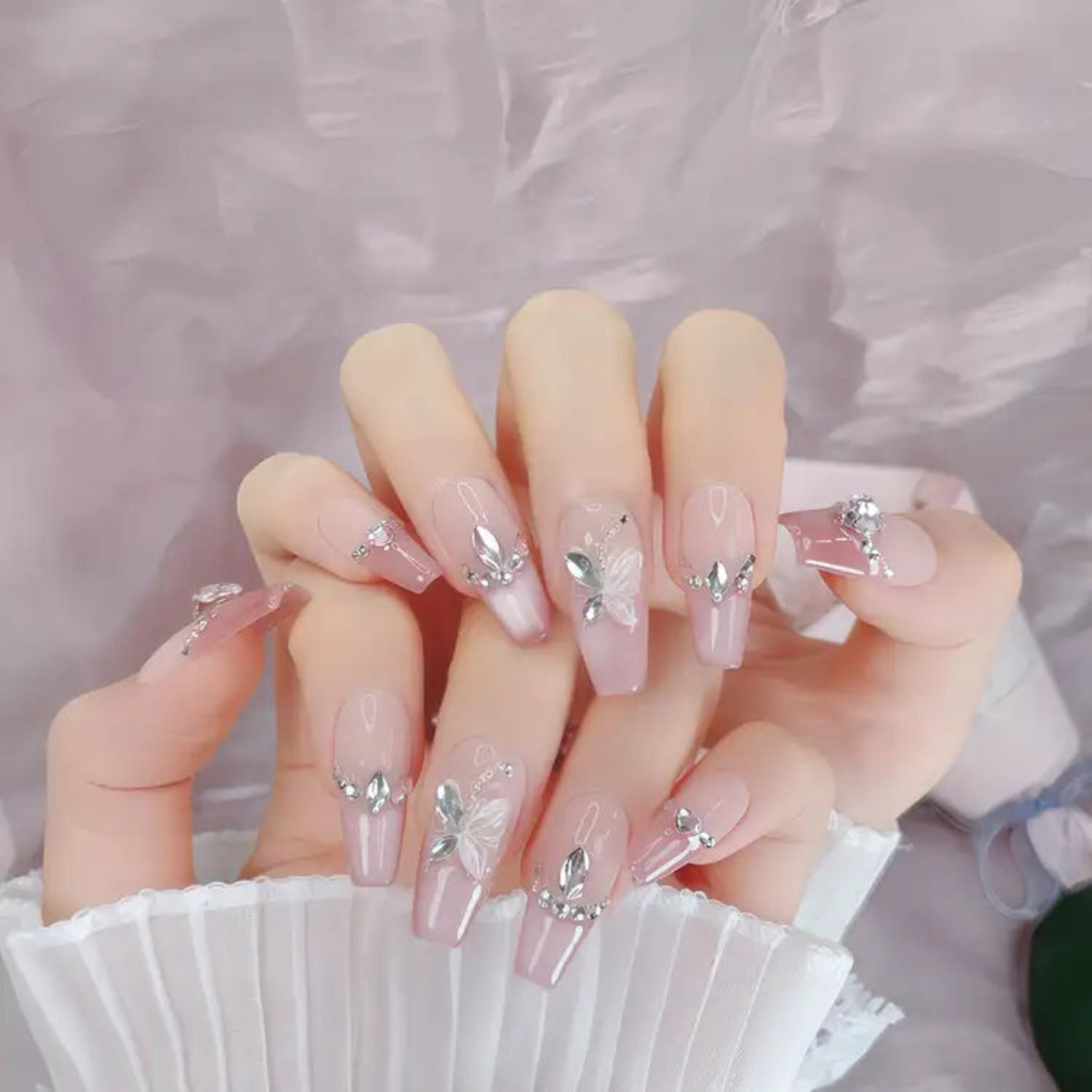 Nails with floral and silver accent designs on a soft pink background