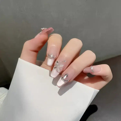 Hand with pink nails featuring butterfly designs against a neutral background