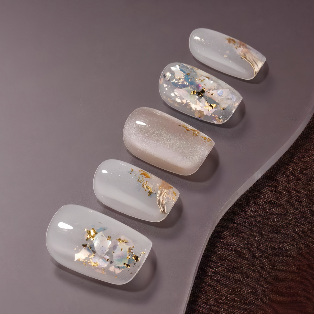 Set of five nail designs with gold and black accents on a gray surface.