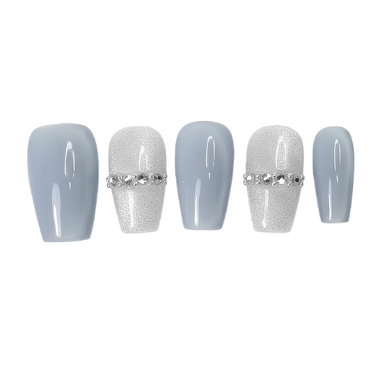 Set of five light blue nail extensions with silver rhinestone decorations on a white background