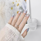 Hand with light purple nail polish and a silver ring on a blurred background