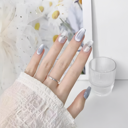 Hand with light purple nail polish and a silver ring on a blurred background