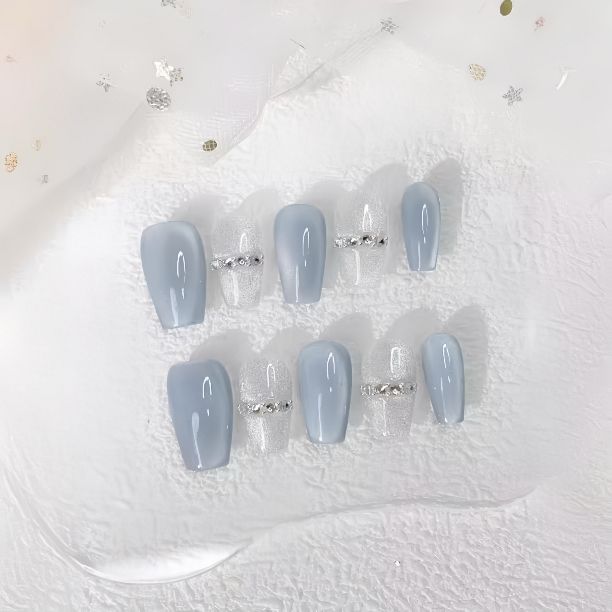 Set of light blue press-on nails with rhinestone decorations on a white background