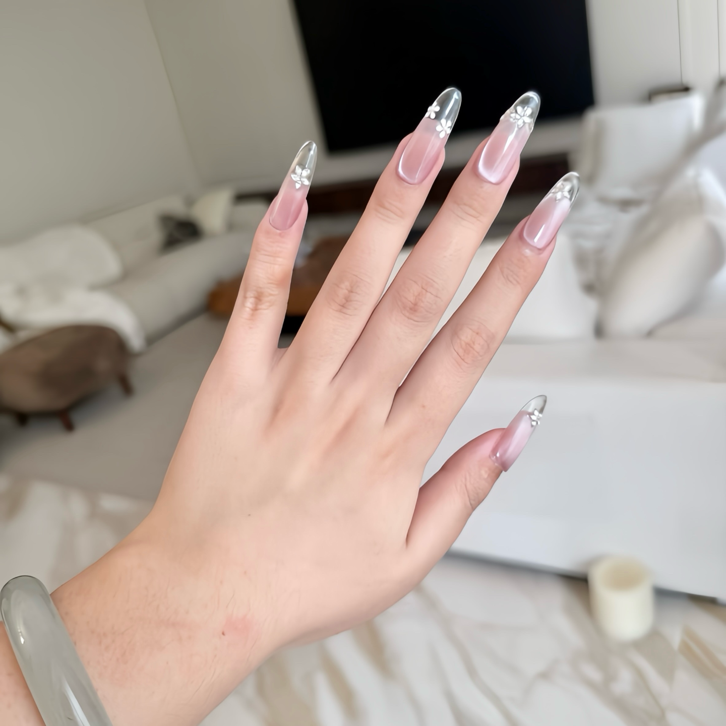 Hand with long, decorative nails in a neutral indoor setting