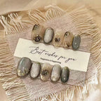 Set of decorative nails with gold accents on a textured surface with a card reading 'Best wishes for you, happiness is happening'.