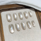 Set of pearl-colored press-on nails on a textured surface