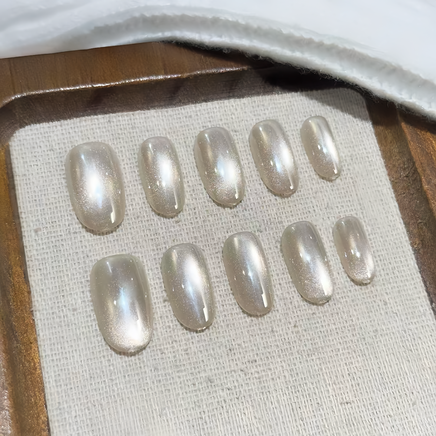 Set of pearl-colored press-on nails on a textured surface