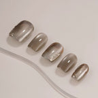 Set of five metallic gray nail polish samples on a light background