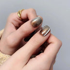 Close-up of hands with metallic nail polish on a neutral background