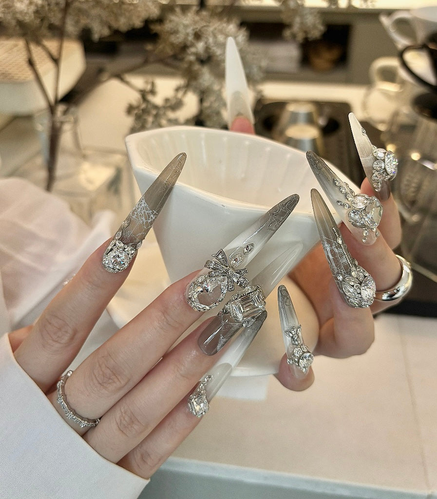 Close-up of hands with decorative nails holding a white cup.