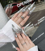 Close-up of hands with decorative nails and rings, blurred background