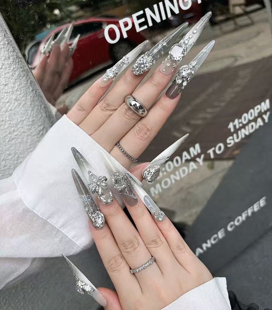 Close-up of hands with decorative nails and rings, blurred background