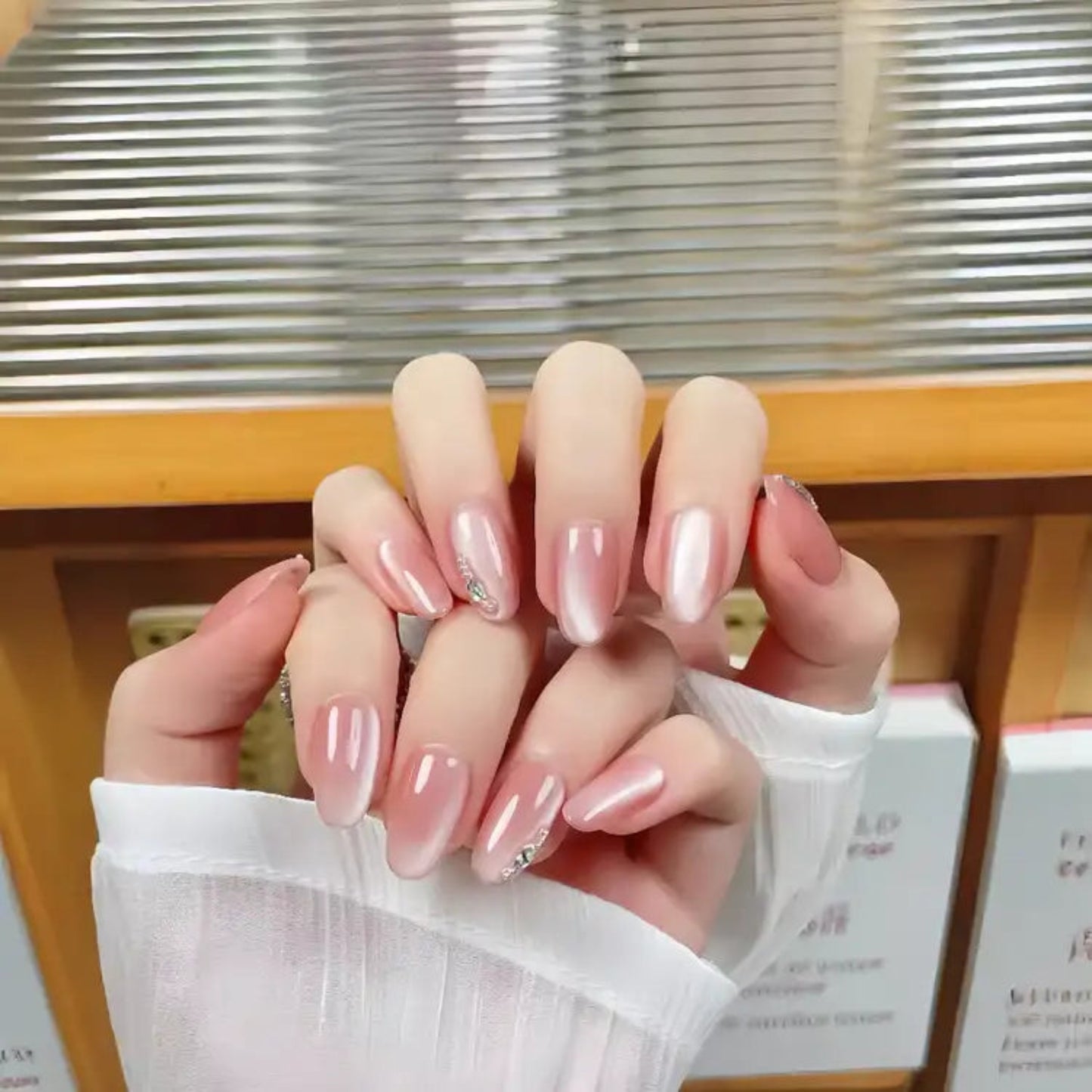 Close-up of a hand with pink nail polish against a blurred indoor background