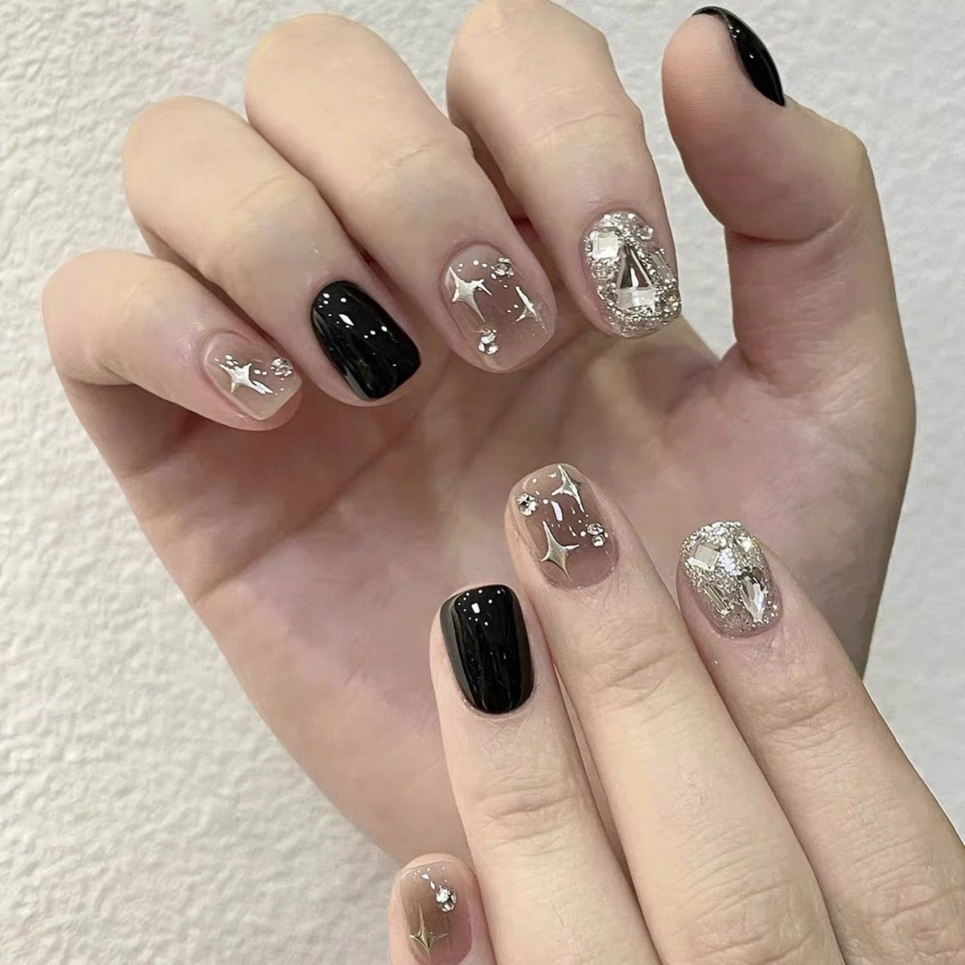 Hand with black and silver nail art on a white background