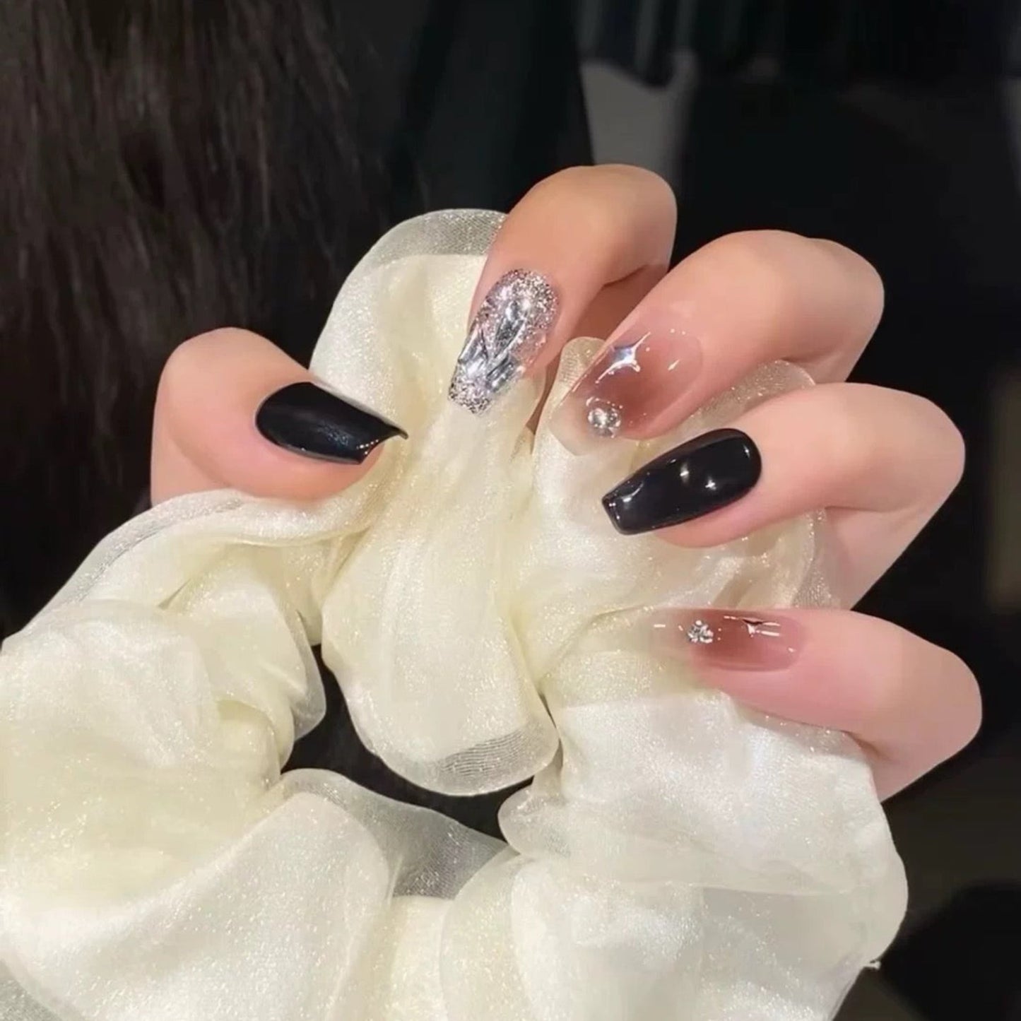 Close-up of hands with decorative nails holding a white scrunchie.