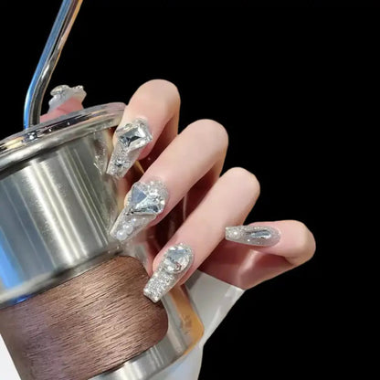 Hand holding a silver and wooden object with decorative nails featuring gemstone designs.